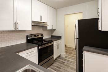 A kitchen with black appliances and white cabinets.